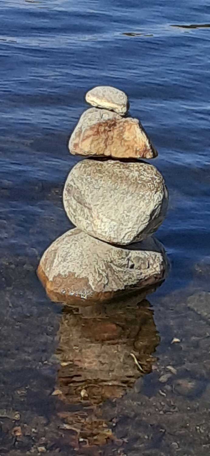 A stack of rocks balanced on each other in shallow water